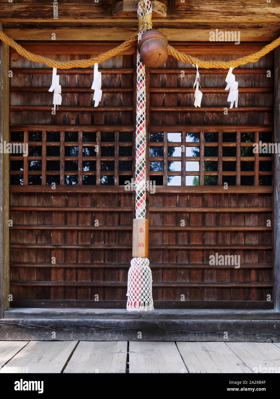 Close-up von Suzu (japanischen Shinto Bell) und das Seil unter der Traufe des Mitake Shinto Schrein hängen. Die Texte auf dem Seil bedeutet: Votive bietet. Stockfoto