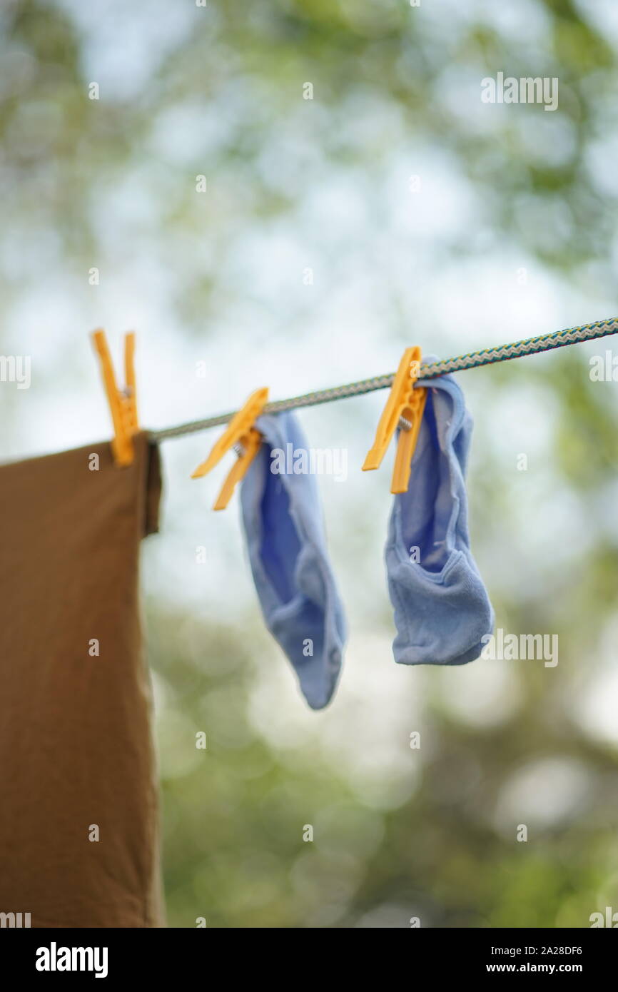 Blaue Socken sind auf einem Seil mit Wäscheklammern im Garten getrocknet Stockfoto