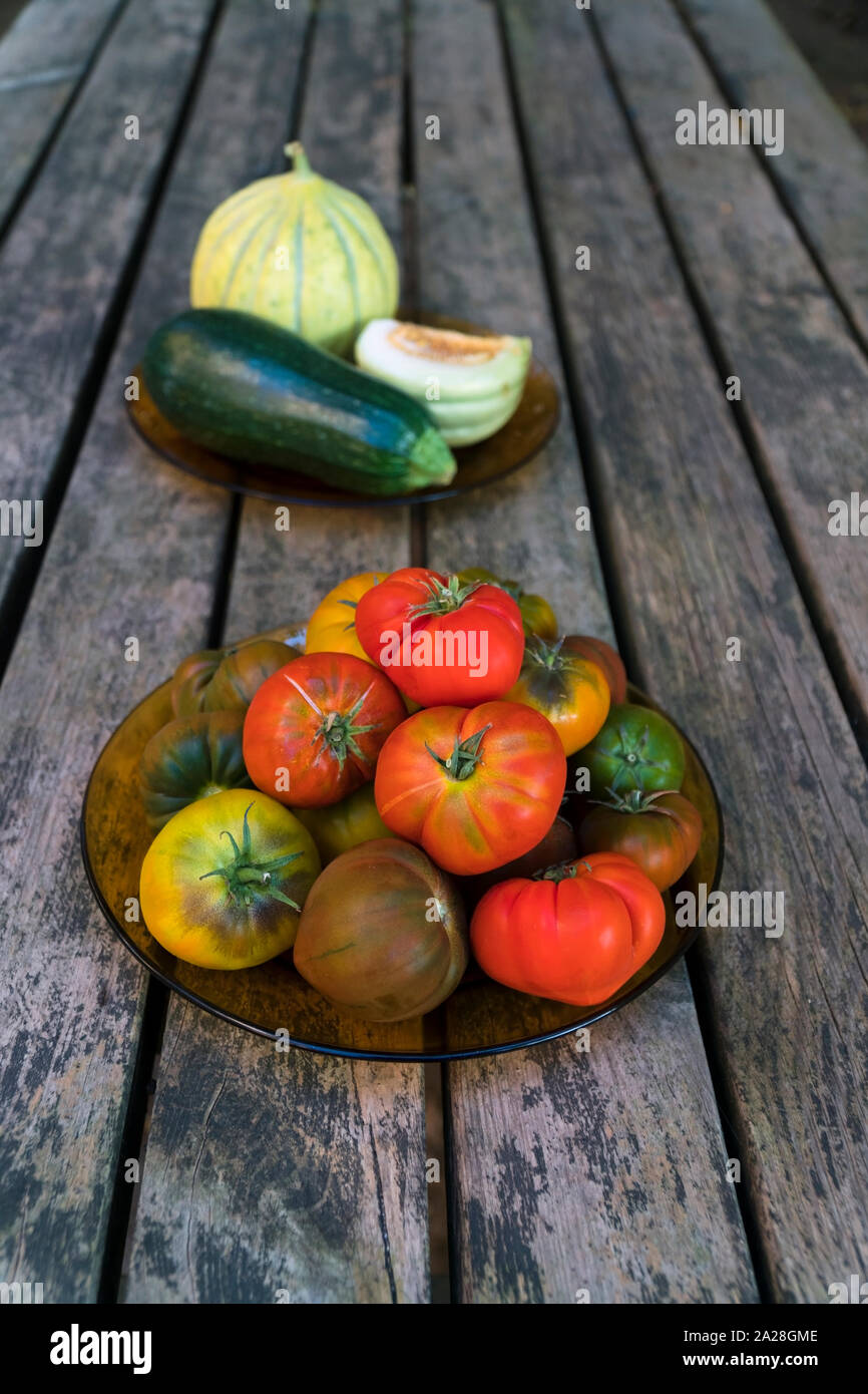 Organische Schokolade Tomaten und rote Tomaten, Zucchini, Melonen sind auf einem Holztisch mit natürliches, weiches Licht Stockfoto