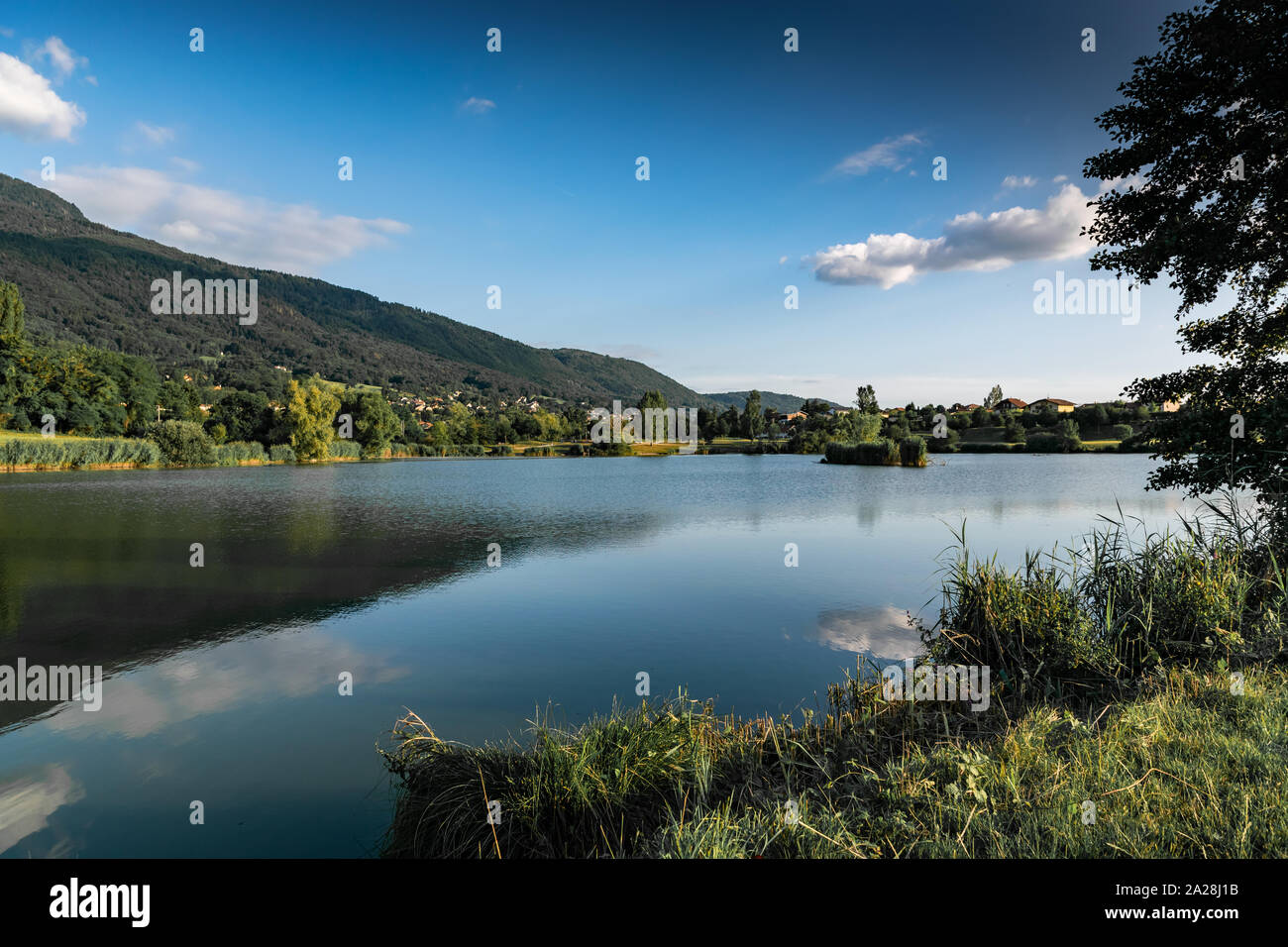 Landschaft, der See, die Berge, Vegetation, Dorf und blauer Himmel mit weißen Wolken, Schwerpunkt in der Mitte des Bild. See Machilly. Stockfoto