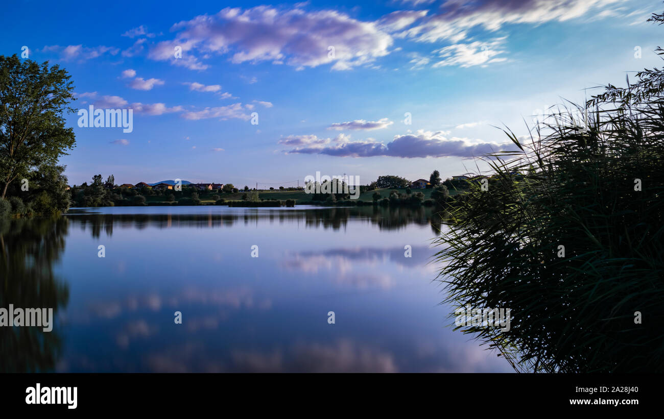 Landschaft, der See, die Berge, Vegetation, Dorf und blauer Himmel mit weißen Wolken. Foto mit grau Filter und langen Belichtungszeit. See Machilly. Stockfoto