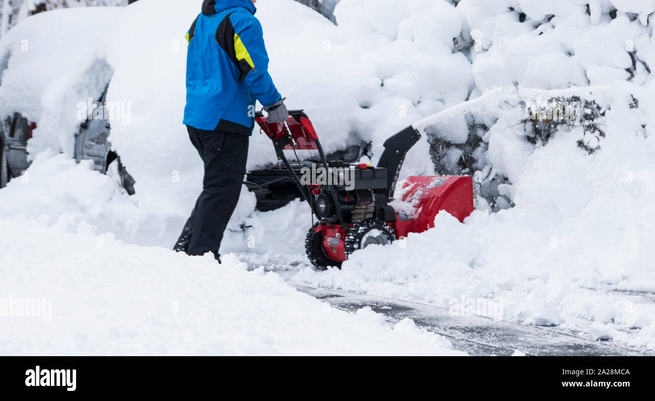 Ein Hausbesitzer ist ihre cleariing drivway mit einem roten Schneefräse nach einem Frühling Schnee Sturm. Stockfoto