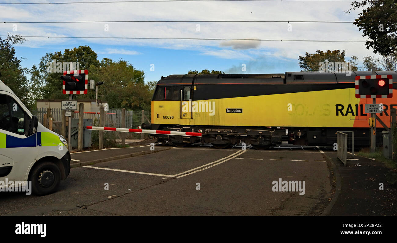 Eine schwarz-gelbe Diesellok kreuze Holywell bahnübergang als Polizei van wartet es auf der Nebenbahn nach lynemouth Power Station zu übergeben. Stockfoto