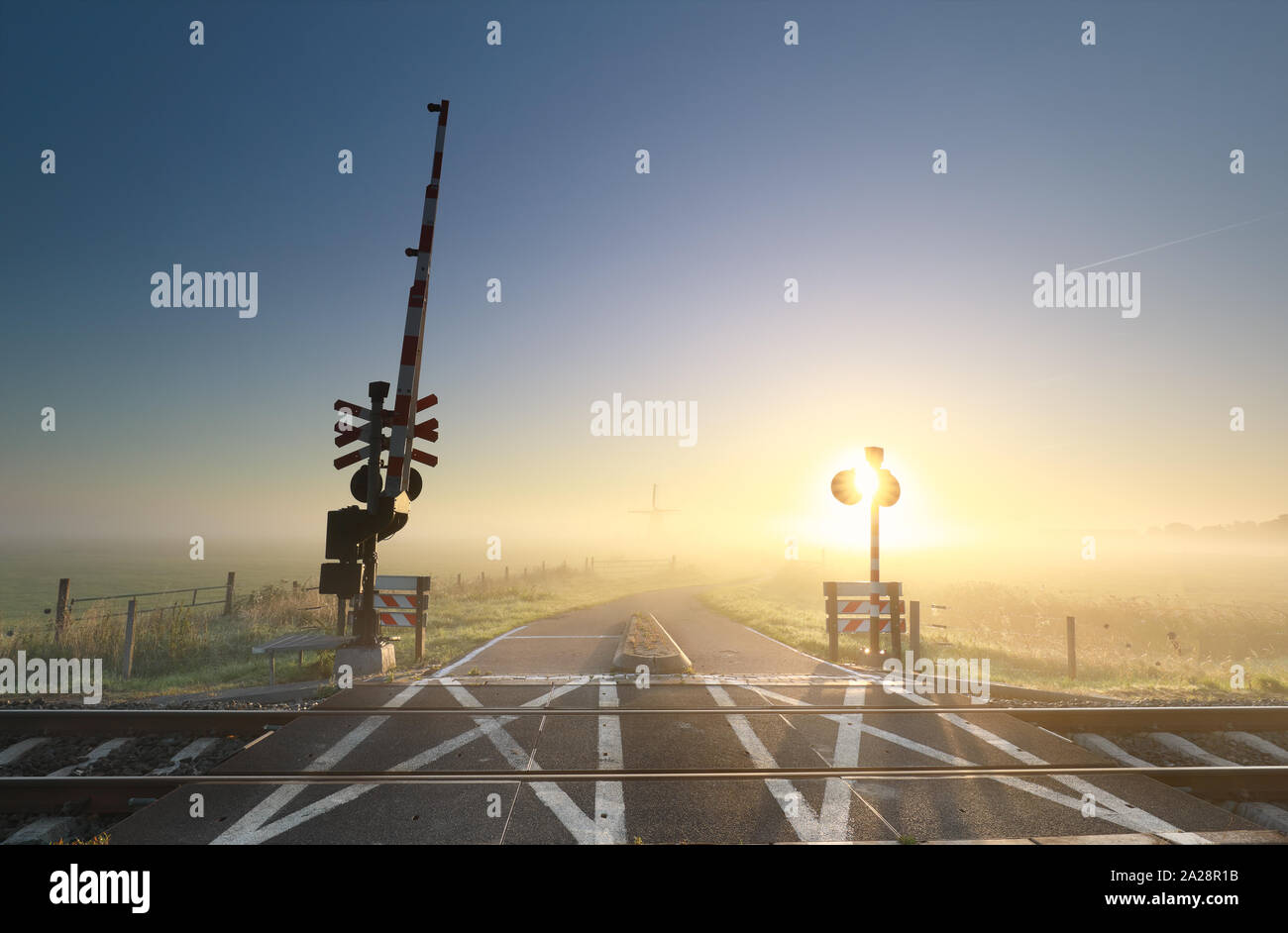 Nebliger Sonnenaufgang über den Bahnübergang auf niederländische Ackerland Stockfoto