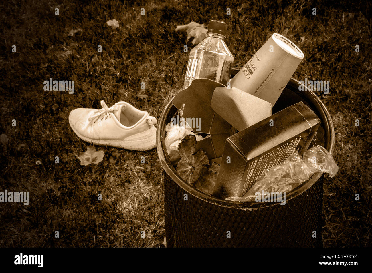 Park Abfallbehälter gefüllt mit random Müll, gemischt von Müll und ein verlegtes Schuh, Sepia Stockfoto