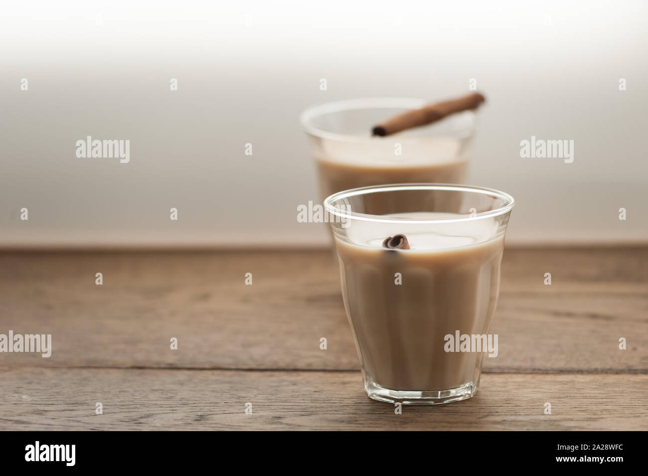 Indische Masala Tee mit Zimtstangen in zwei Gläser auf Holz- Hintergrund. Selektive konzentrieren. Natürliches Licht. Horizontal mit kopieren. Stockfoto
