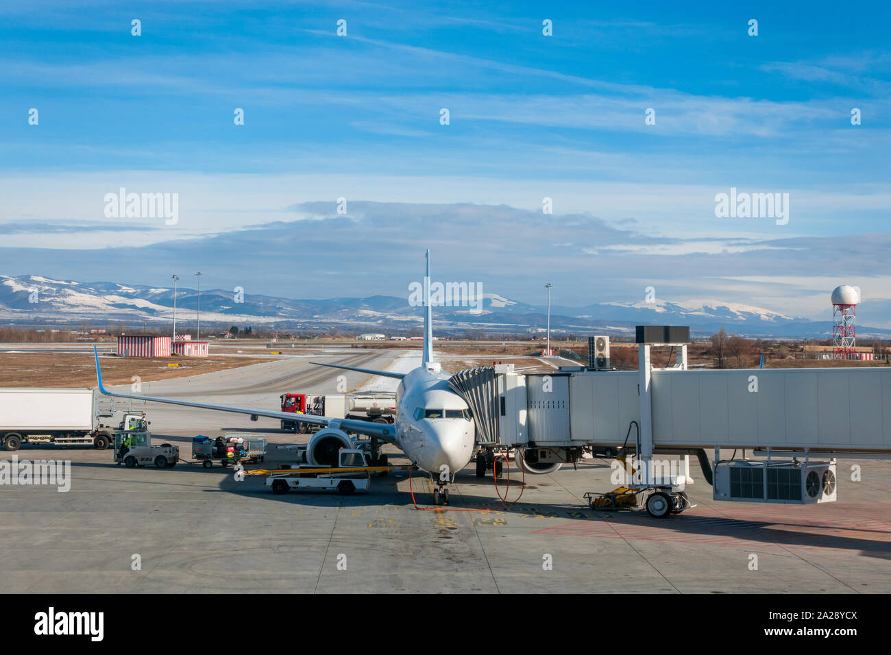 Flugzeug, Jet Airliner Betankung mit Gehweg befestigt und Gepäck auf der Landebahn Schürze am Flughafen Sofia, Bulgarien, Europa hochgeladen werden im Winter Stockfoto