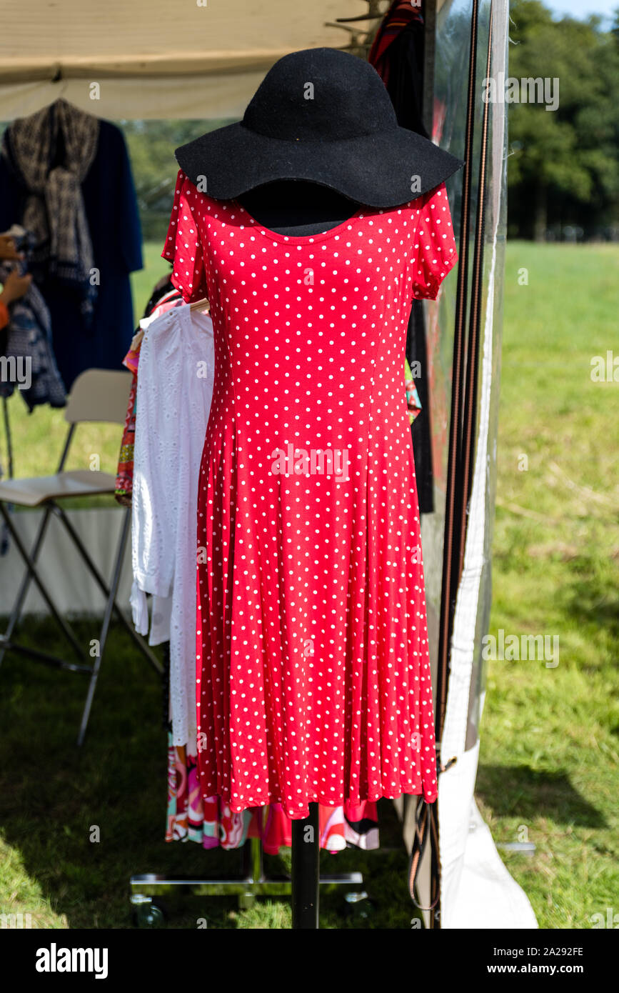 Rot elegante Mode Damen rotes Kleid mit kurzen Ärmeln mit einem kleinen weißen Punkten Design und schwarzen Filzhut präsentiert auf einer Schaufensterpuppe an einem sonnigen Tag in einem Stockfoto