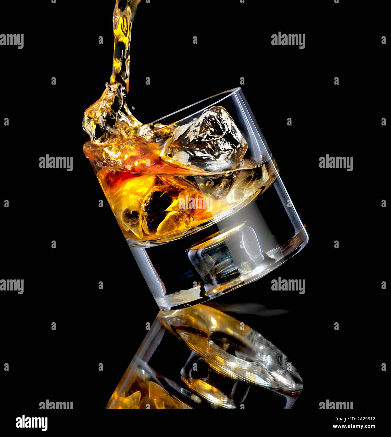 Gießt Whiskey in Glas gekippt über Würfel von Eis auf schwarzen Hintergrund mit Reflektion Stockfoto