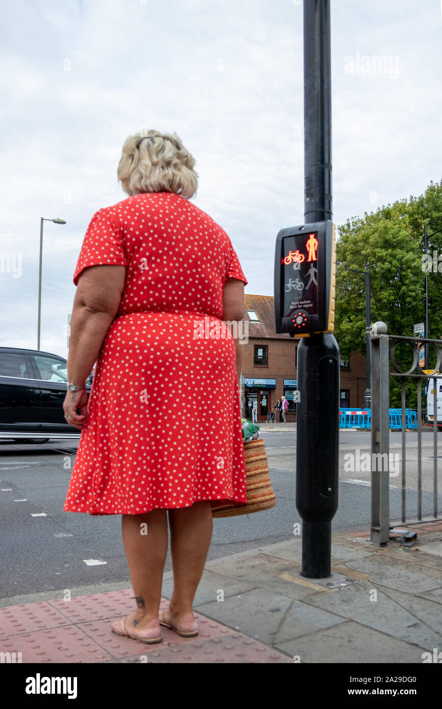 Eine Frau mittleren Alters warten auf ein grünes Licht an einer Ampel Stockfoto