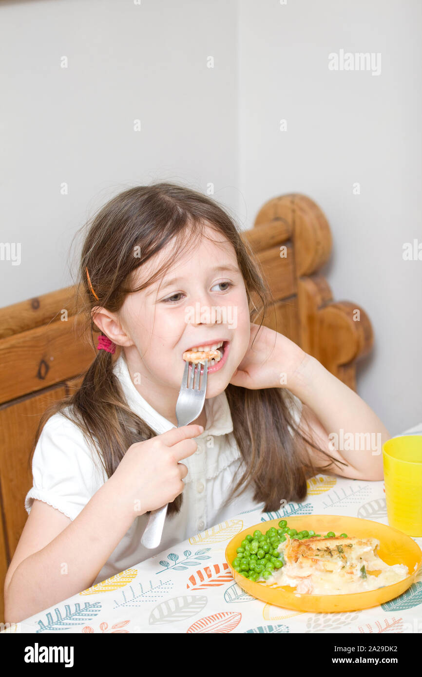 6-Jähriges Mädchen essen Fisheye am Tisch Stockfoto