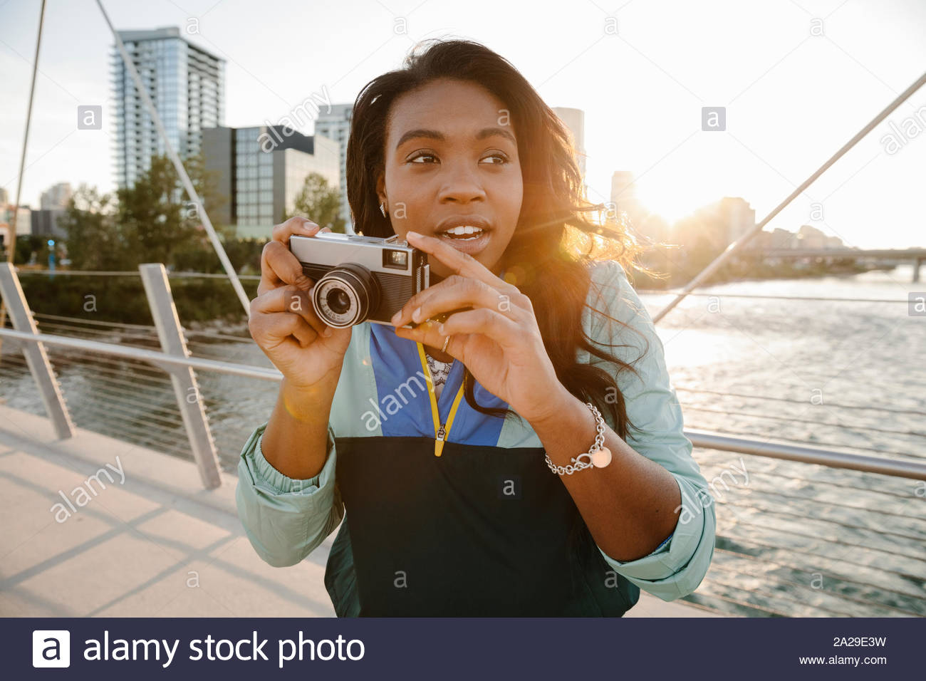 Junge Frau mit retro Kamera an sonnigen, städtische Brücke Stockfoto