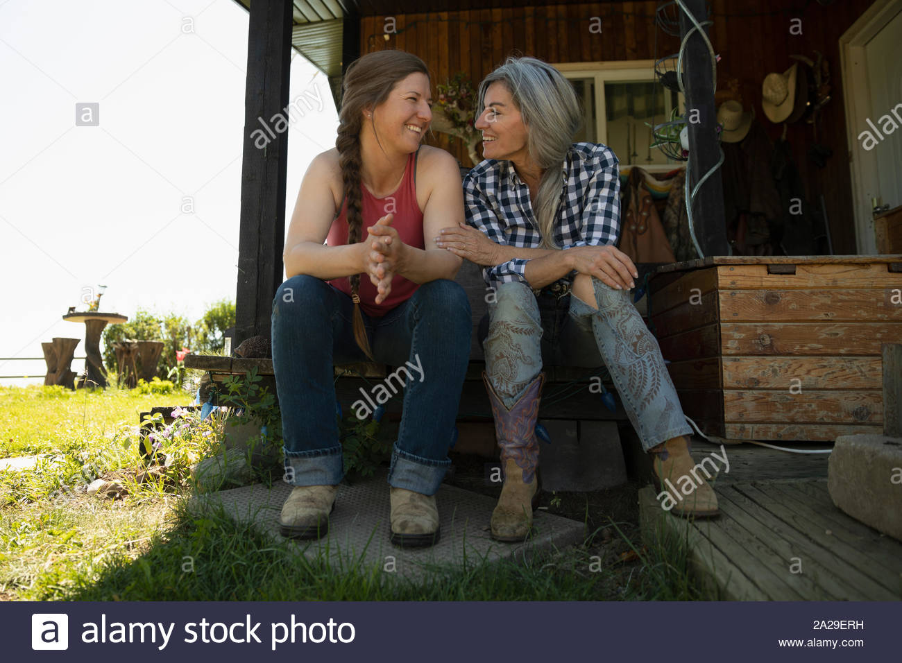 Mutter und Tochter sitzen auf Ranch Halle reden und lächeln Stockfoto
