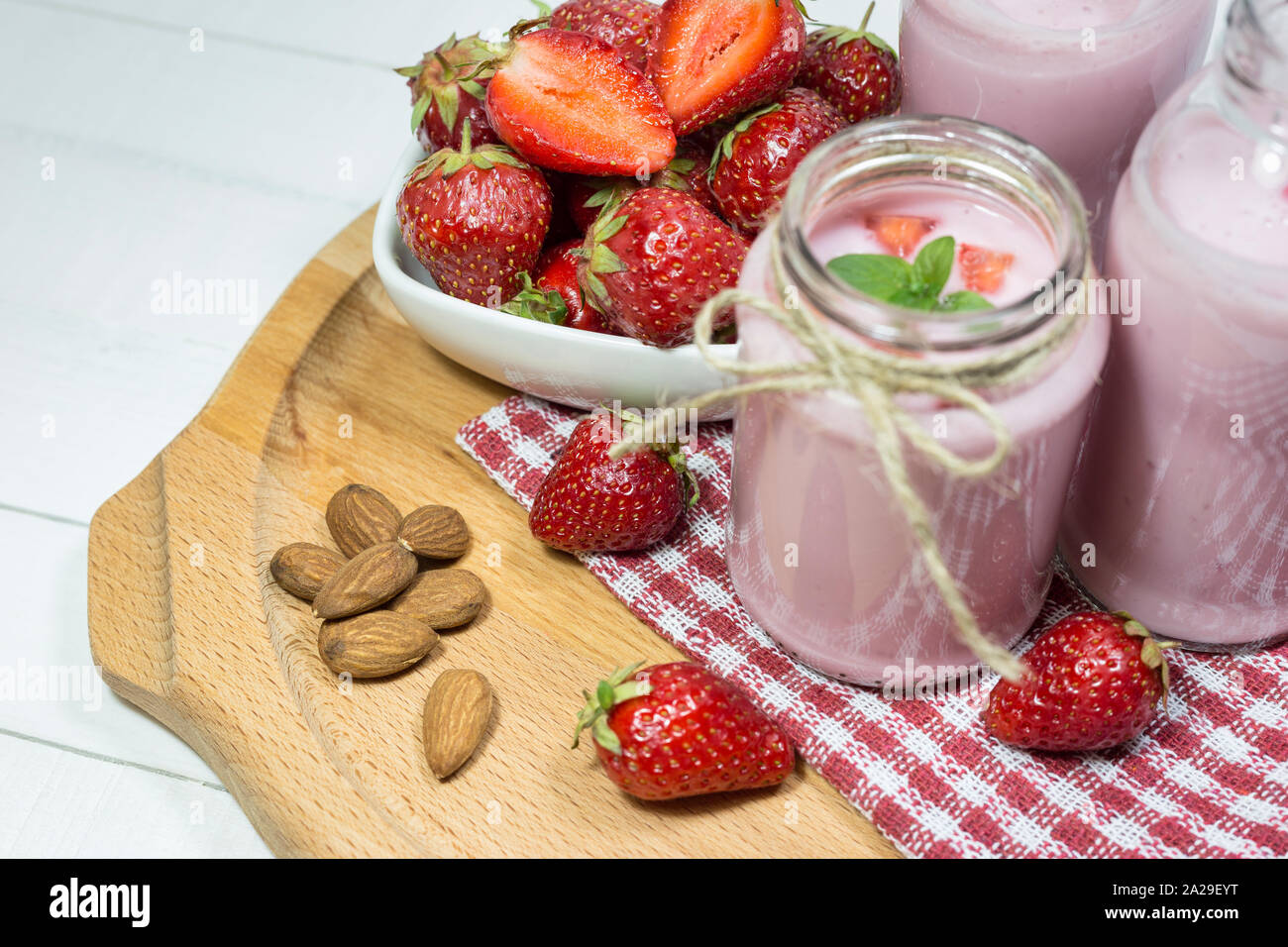 Frische Erdbeeren, Mandeln und hausgemachte Frucht Joghurt auf Holzplatte. Gesunde Ernährung Konzept. Stockfoto
