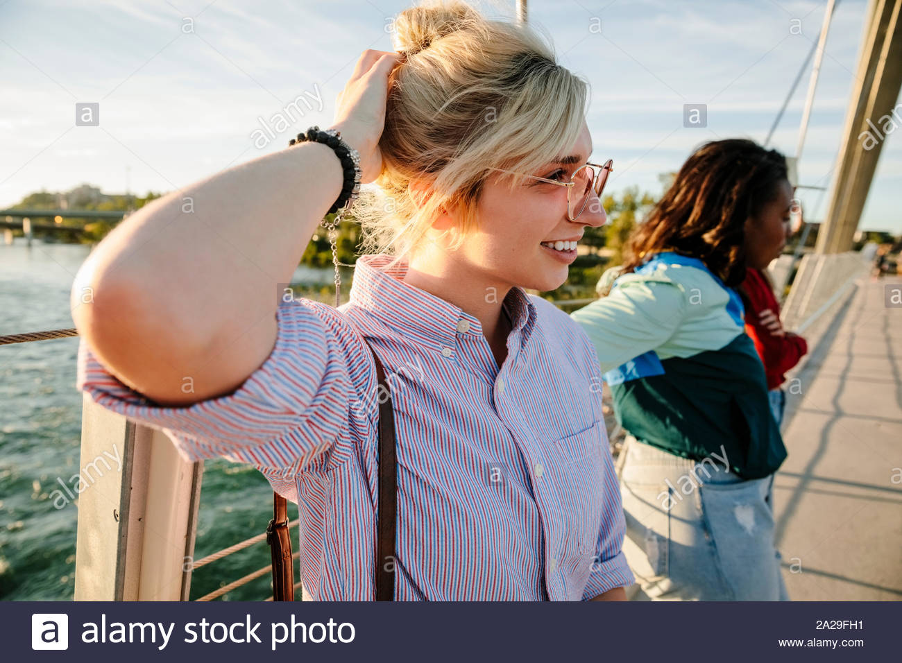 Glückliche junge Frau auf sonnigen Brücke Stockfoto