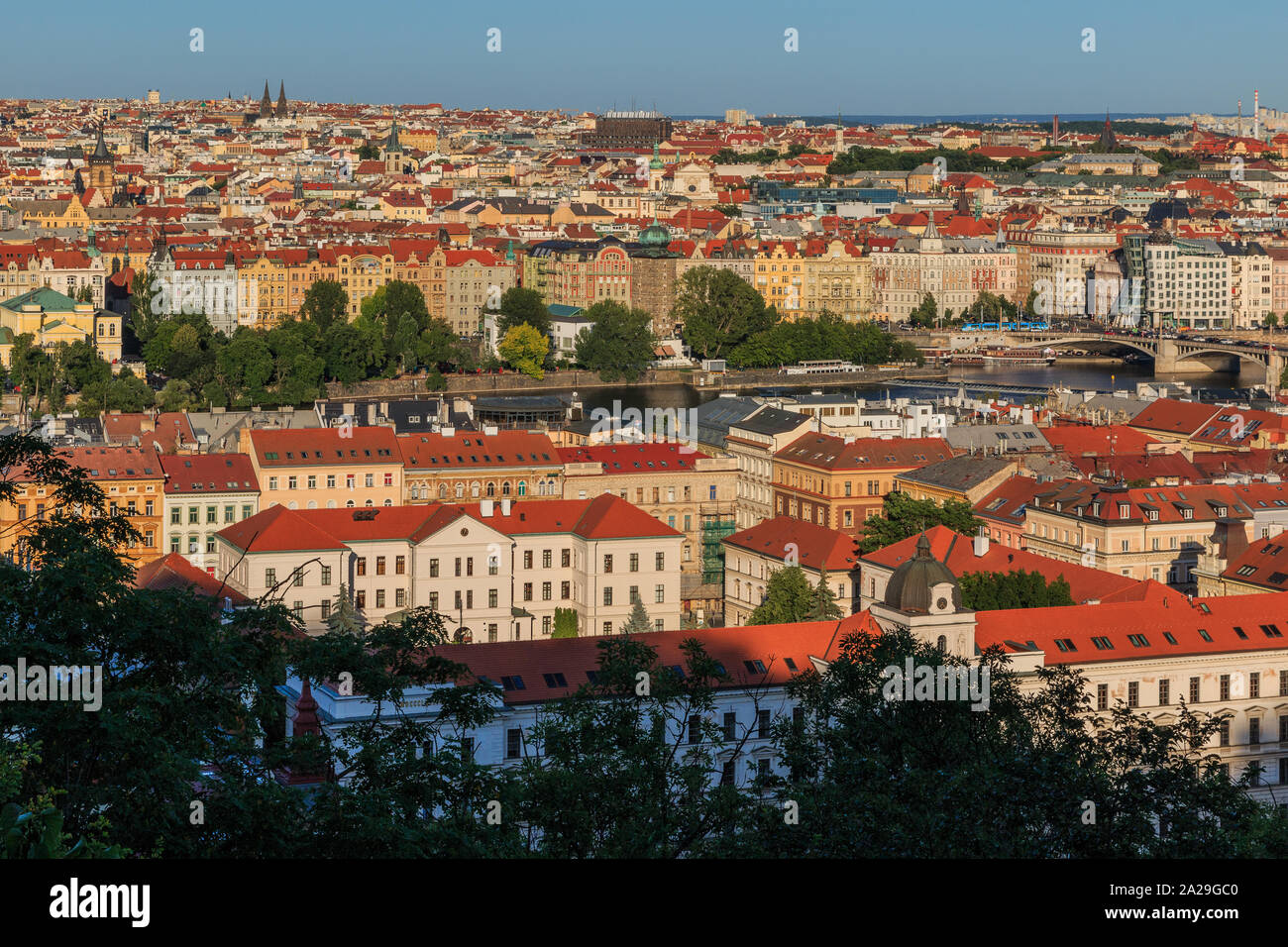 Blick über die Dächer und historischen Gebäuden von Prag die Hauptstadt der Tschechischen Republik an einem sonnigen Tag mit blauen Himmel und Büsche im Vordergrund. Stockfoto