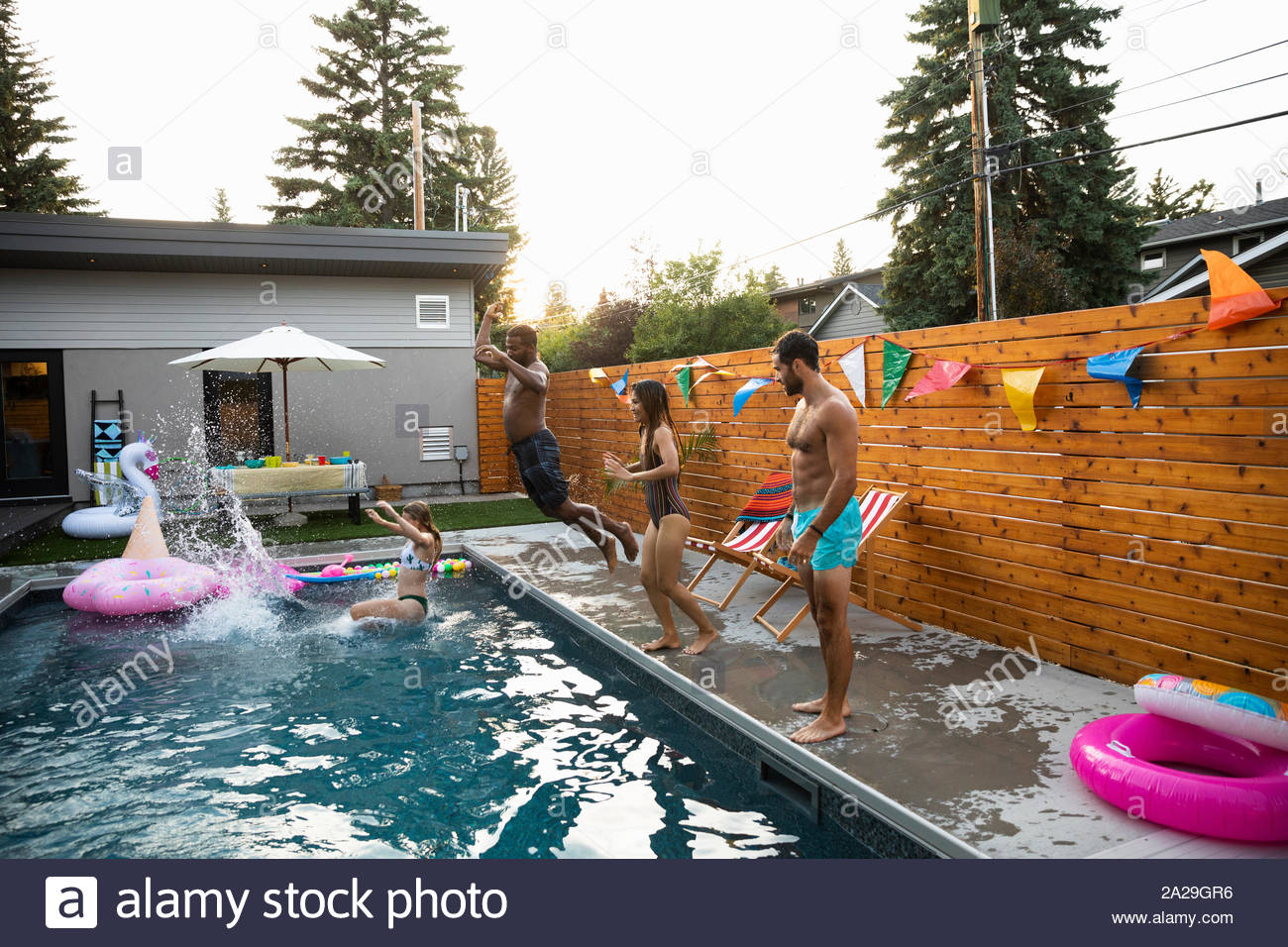 Junge Erwachsene Freunde springen in Sommer Schwimmbad Stockfoto