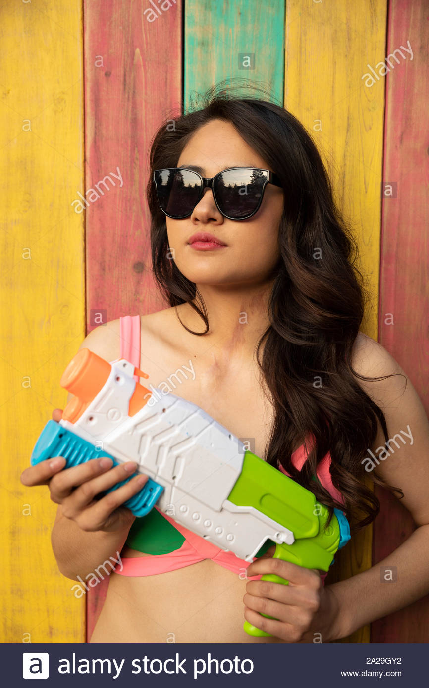 Portrait zuversichtlich, coole junge Frau mit squirt Gun im Sommer Terrasse Stockfoto