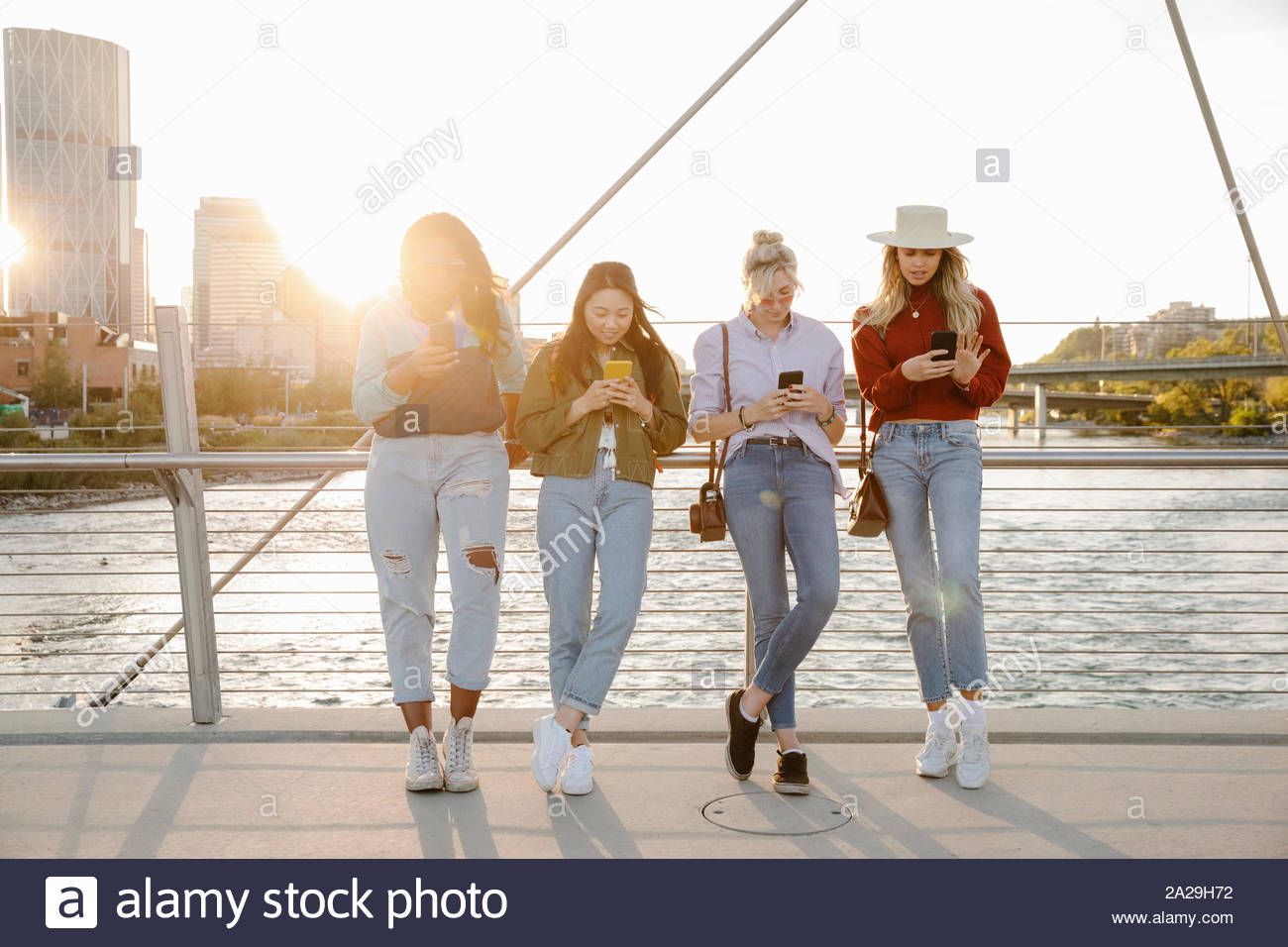 Junge Frauen, die Freunde aus Smartphones an sonnigen, städtische Brücke Stockfoto