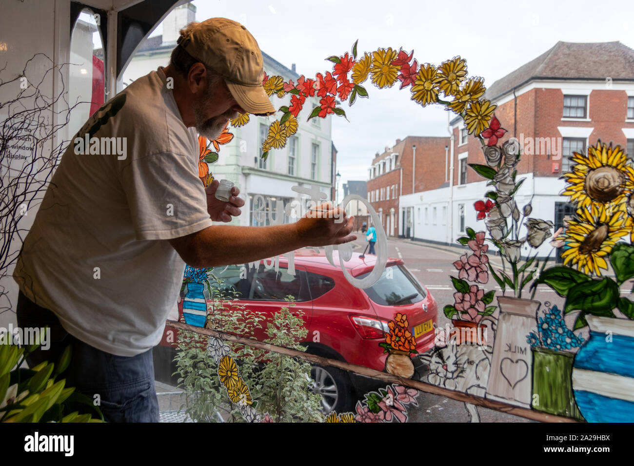 Ein Zeichen Schriftsteller Maler oder Künstler Malerei ein Design auf einem Blumenladen Fenster Stockfoto