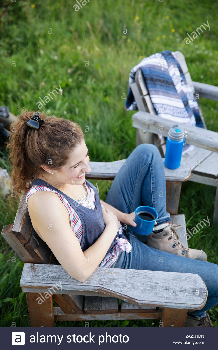 Frau in Holzstuhl sitzend mit Kaffee Stockfoto