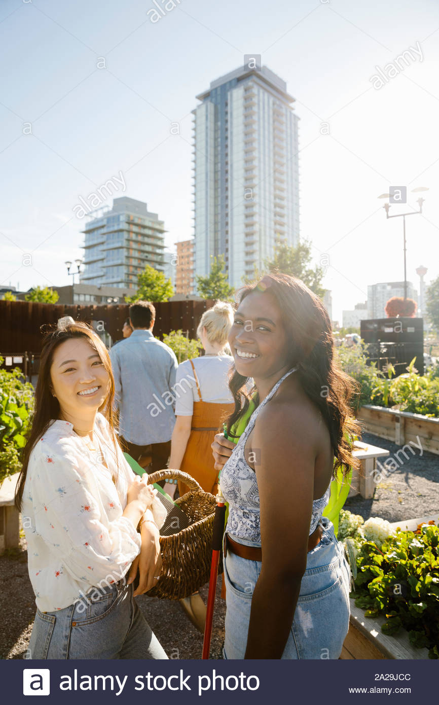 Portrait glückliche, unbeschwerte junge Frauen Freunde in sonniger, städtischen Gemeinschaft garten Stockfoto