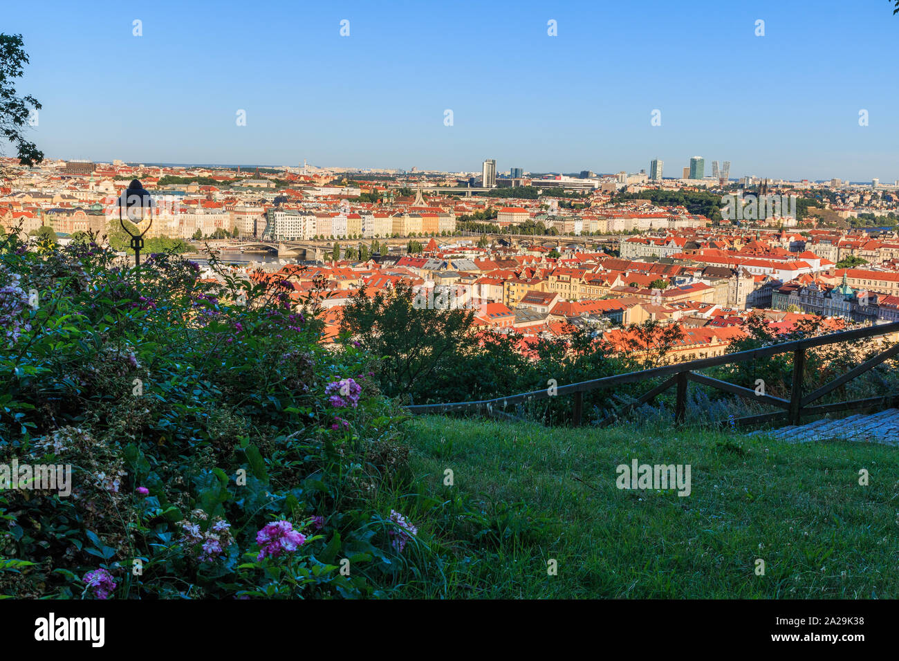 Panoramablick über die Dächer der Stadt und die historischen Gebäude des Viertels Mala Strana in Prag. Im Vordergrund eine Grünfläche mit lila Blüten ein Stockfoto