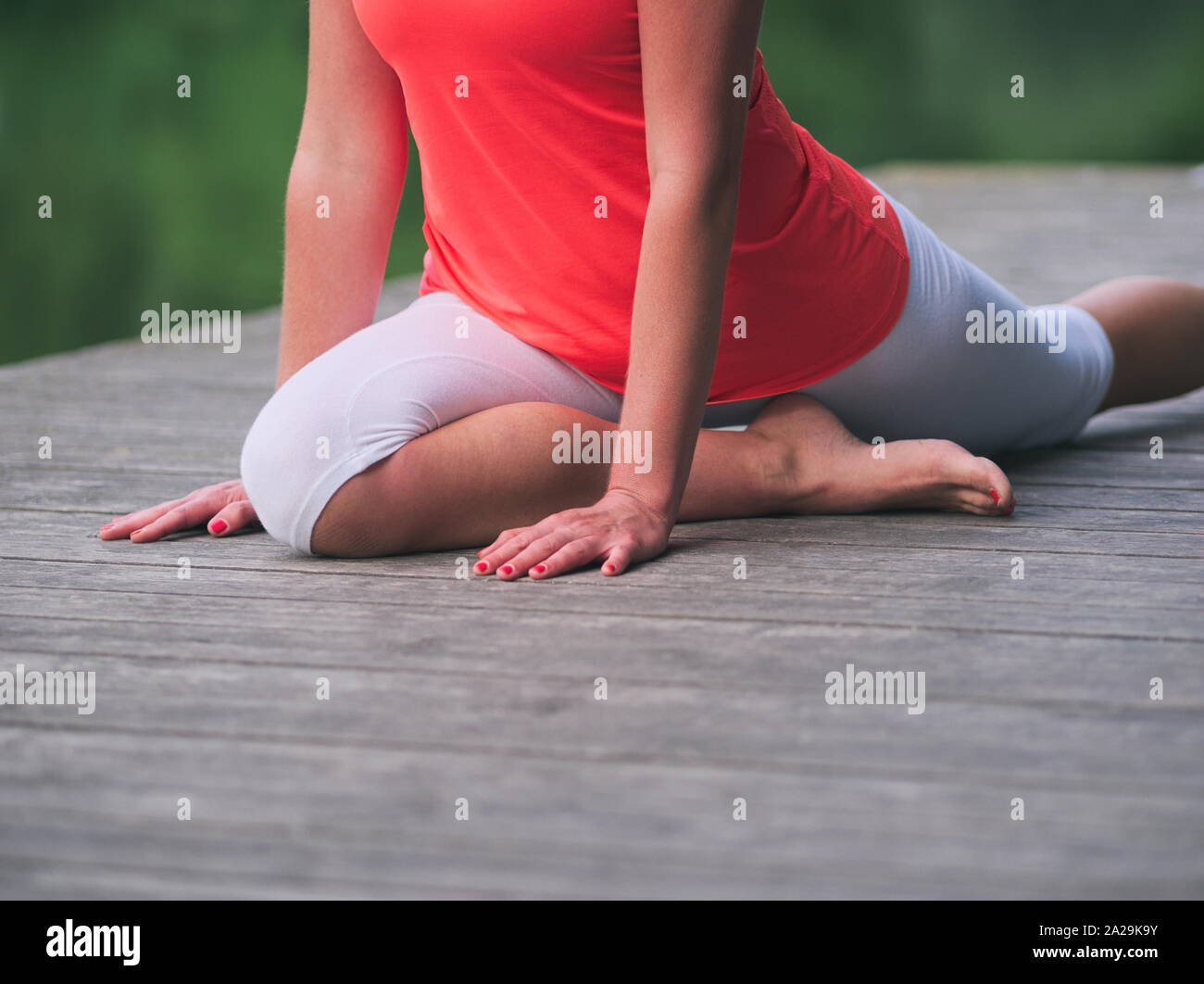Frau in den 30er Jahren Yoga im Park auf einem Pier Stockfoto
