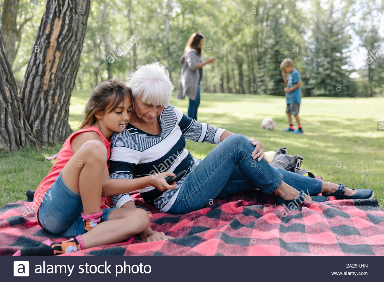 Enkelin, die Großmutter Smartphone auf der Picknickdecke Stockfoto