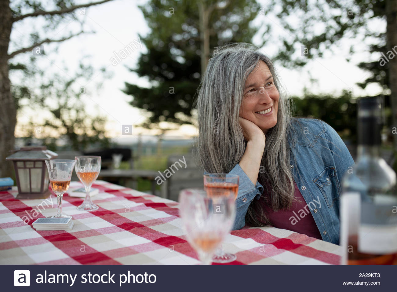 Reife Frau mit langen grauen Haaren entspannen auf Ranch mit Wein Stockfoto