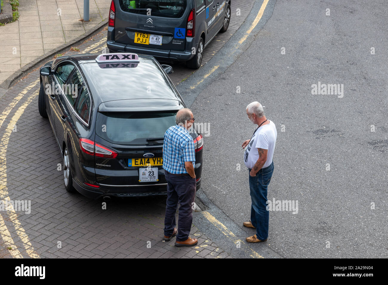 04/01/2019 Havant, Hampshire, UK zwei mittleren Alters oder Taxi Taxifahrer sprechen in der Nähe ihre Autos während des Wartens auf einen Tarif oder Kunde Stockfoto