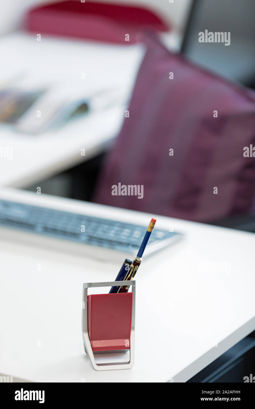 Stifthalter an einem modernen Arbeitsplatz Schreibtisch mit Stuhl Stockfoto