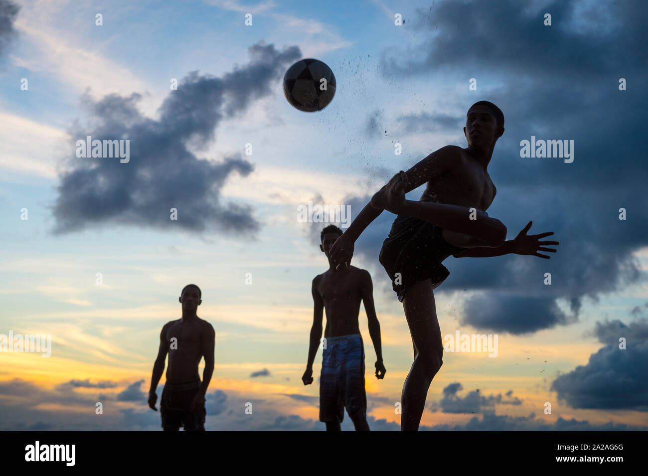 BAHIA, BRASILIEN - 15. Februar, 2018: Junge Männer spielen eine informelle Spiel der Fußball-Keepy Uppy in Silhouette am Ufer eines Sunset Beach. Stockfoto