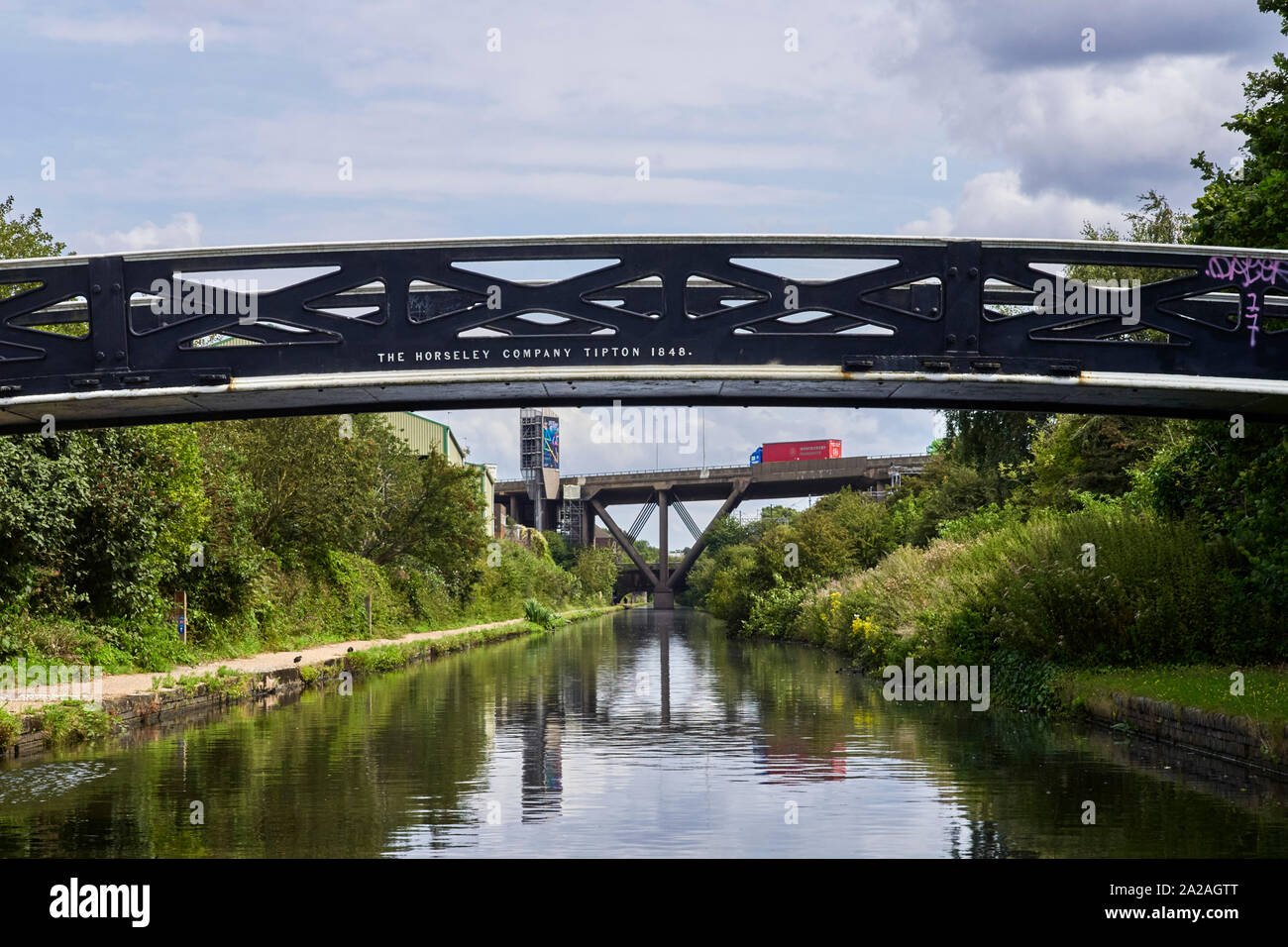 Blick entlang der Linie Kanal in das Zentrum von Birmingham mit einem traditionellen Iron Bridge im Vordergrund und die Autobahn M5 hinter Stockfoto