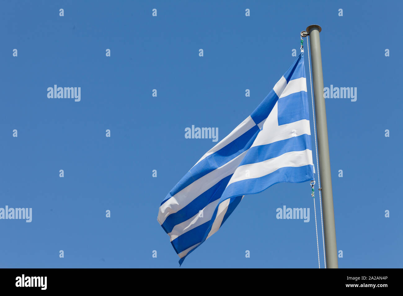 Die griechische Flagge, die hoch in einem klaren blauen Himmel liegt. Stockfoto