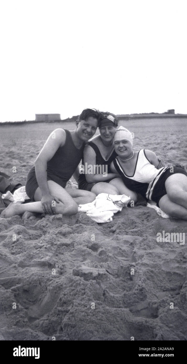 1930er Jahre, historisch, ein Mann und zwei Damen sitzen an einem Sandstrand in den Badeanzügen der damaligen Zeit, England, Großbritannien. Stockfoto