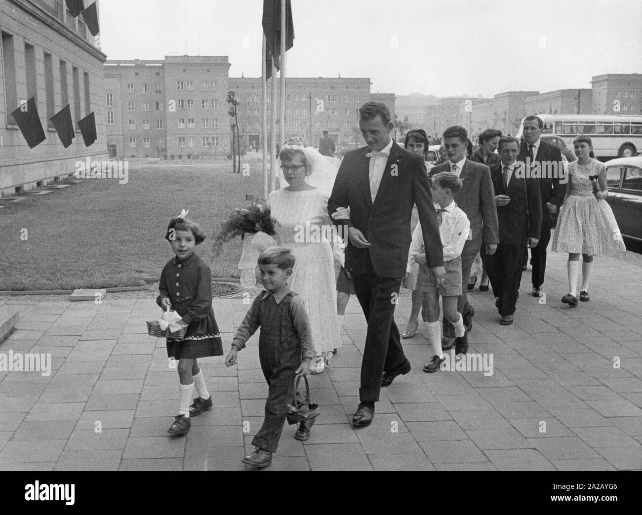 Braut und Bräutigam mit Hochzeit Party in Stalinstadt, DDR. An der Vorderseite, zwei Kinder mit Blumenkörben. Stockfoto