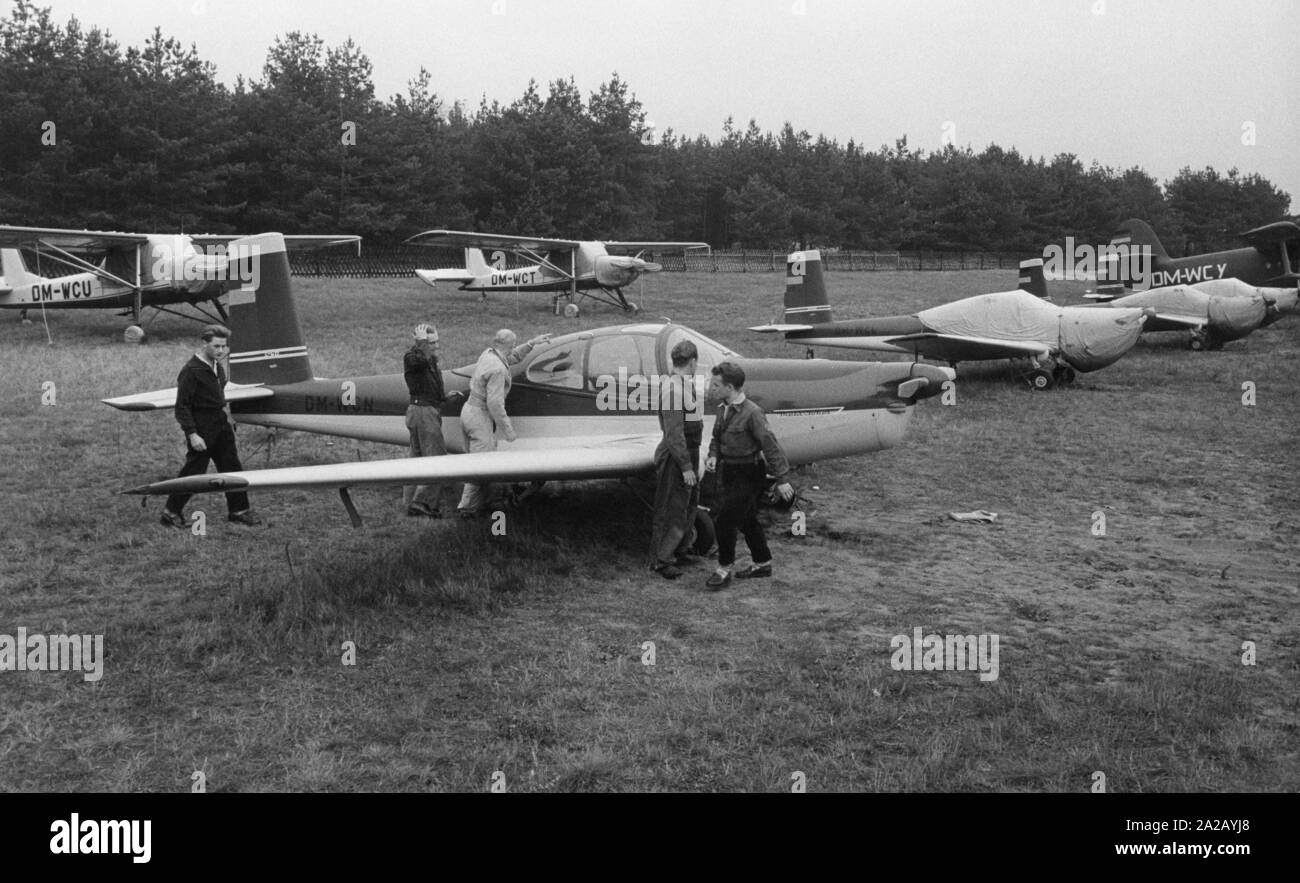 Die Gesellschaft für Sport und Technik (GST) (Sport und Technology Association) war eine paramilitärische Jugendorganisation in der DDR. Es wurde eingerichtet, um die Freizeit der jungen Leute, die sich für Sport und Technologie zu organisieren. Im Bild: der Flugplatz Schönhagen in der Mittelmark Region, wo leichte Flugzeuge abgestellt sind und einige Mitglieder. Stockfoto