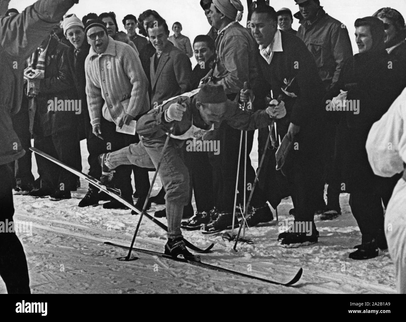 Das Bild zeigt die Teilnehmer der 30 km Langlauf bei den Olympischen Winterspielen 1956 in Cortina d'Ampezzo. Es ist Veikko Hakulinen aus Finnland, der auch die Goldmedaille bei diesem Rennen gewonnen. Die Ziellinie ist durch Presse und Fans, die ihn umgeben, sind ermutigend. Stockfoto