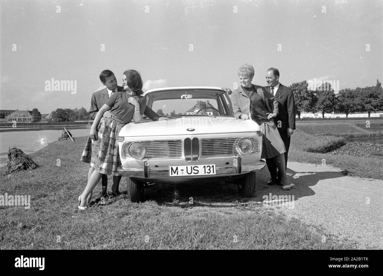 Zwei Männer und zwei Frauen mit einem BMW 1800 Auf dem Weg in den Park von Schloss Nymphenburg posieren. Stockfoto