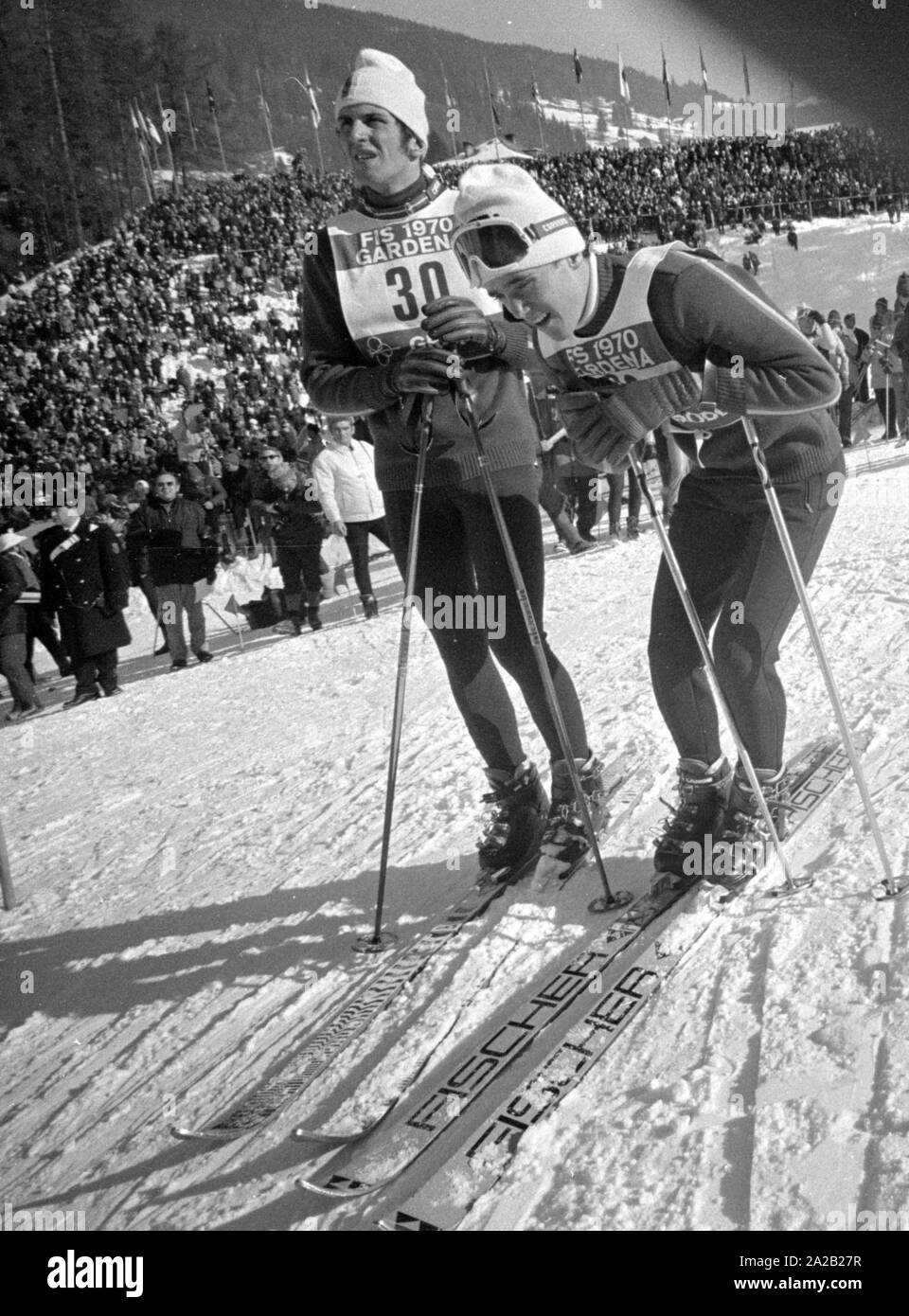 Die Alpine Ski-WM in Val Gardena zwischen 7.2.1970 und 15.2.1970, und er hatte die nur Wm so weit, deren Ergebnisse die Alpine Ski WM enthalten. Zwei Skifahrer schauen Sie oben an der Piste nach ihren Lauf in einem der Wettbewerbe. Stockfoto