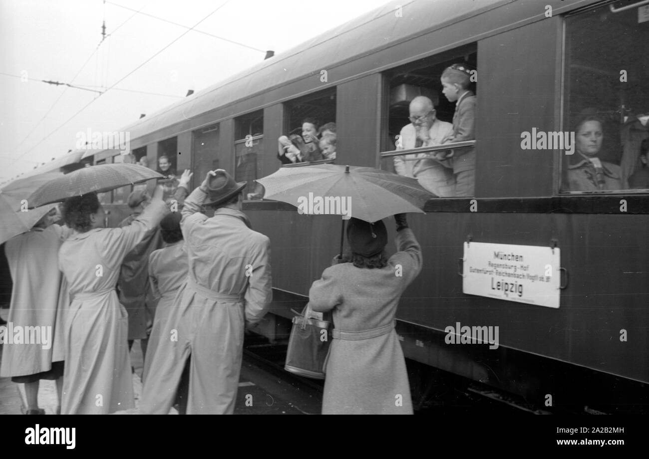 Bahnreisende werden von Verwandten und Freunden auf der Plattform eines Bahnhof gesehen. Foto der interzonal Zug auf der Strecke Leipzig-Gutenfuerst - Hof-Munich. Dieser Zug wurde für seine "Deutschen" Speisewagen, die beliebt wegen der 1 wurde bekannt: 1 Wechselkurs, besonders unter Ostdeutschen Reisende. Stockfoto