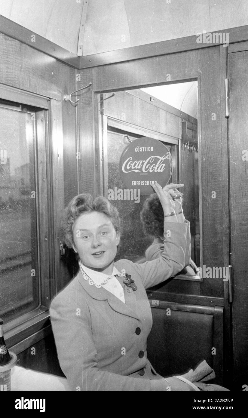 Foto der interzonal Zug auf der Strecke Leipzig-Gutenfuerst - Hof-Munich. Dieser Zug wurde für seine "Deutschen" Speisewagen, die beliebt wegen der 1 wurde bekannt: 1 Wechselkurs, besonders unter Ostdeutschen Reisende. Foto einer Dame, die Coca Cola aus der Kellner zu bestellen. Da jedoch die Verwaltung der Osten Deutschland den Verkauf von amerikanischen Produkten in dieser Speisewagen untersagt, das Getränk war auch nicht verfügbar. Das Plakat hängt es irgendwie. Stockfoto