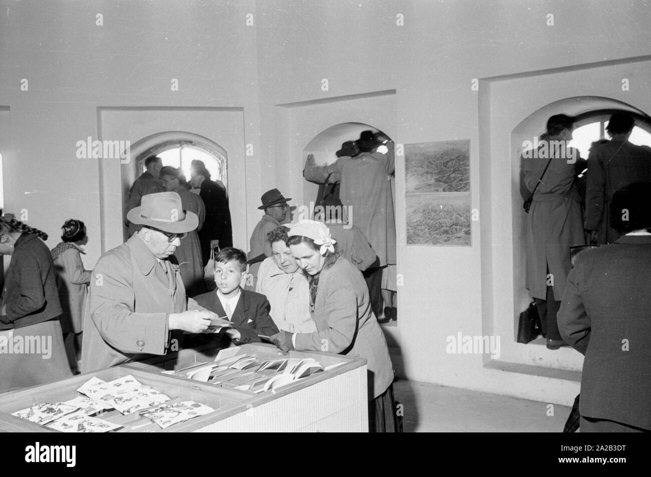 Einige Besucher sind auf der Suche nach Souvenirs im Südturm der Münchner Frauenkirche, und aus den Fenstern auf die Altstadt blicken. Im Jahr 1954 wurde ein neuer Aufzug wurde installiert, die in der Lage war, viele Besucher bis an die Spitze zu bringen. Dieses Bild war wahrscheinlich auf der Eröffnung Tag der neue Aufzug genommen. Stockfoto