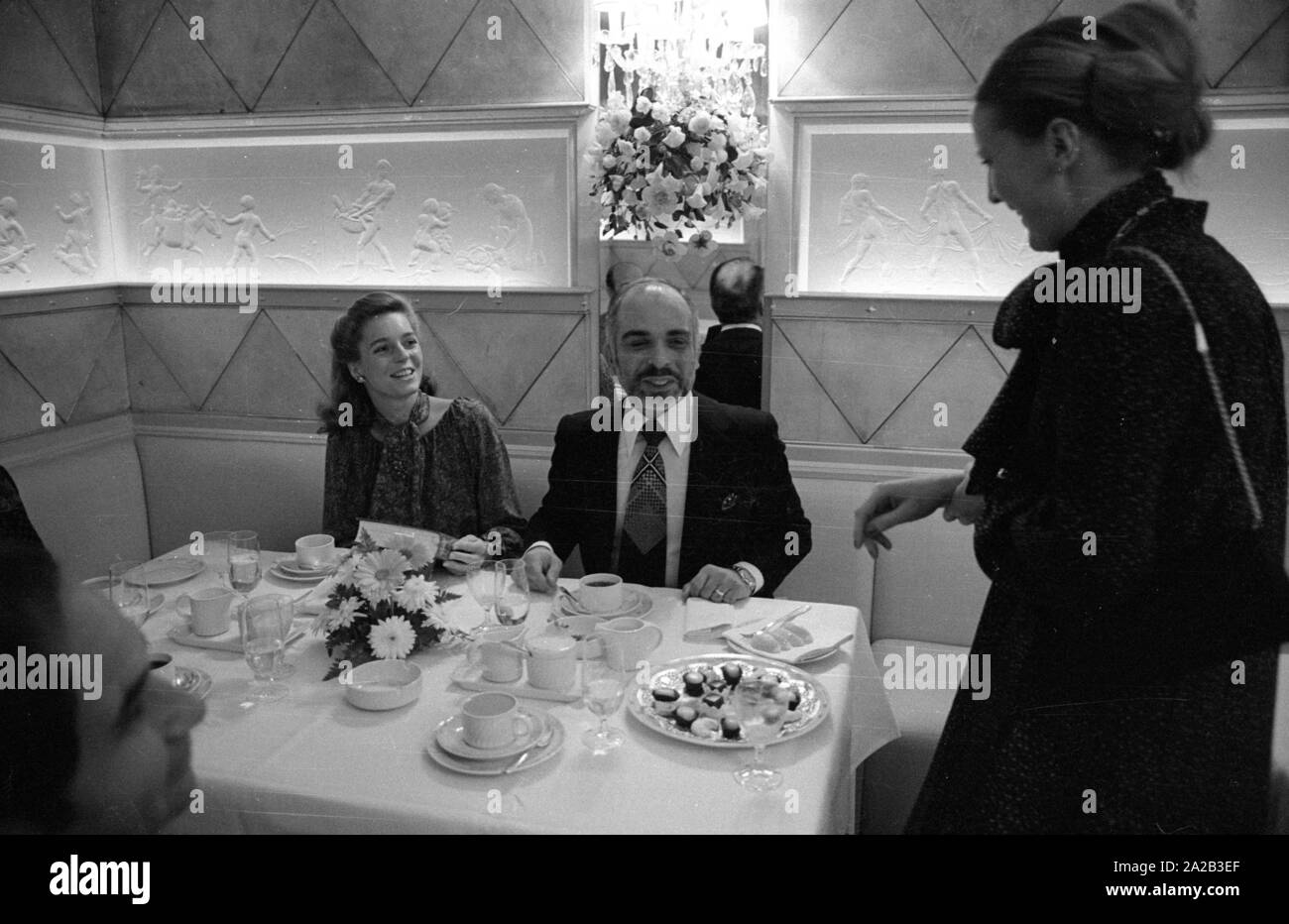 Nach einer diplomatischen Konferenz in Bonn, dem jordanischen König Hussein ich ein paar Tage in Berchtesgaden verbracht mit seiner Frau Königin Nur (zivile Name: Lisa Halaby), jedoch anlässlich seines Geburtstages sie im Hotel "Vier Jahreszeiten" in München verbracht. Das Bild zeigt das königliche Paar am Tisch mit Gästen, König Hussein erhält ein Geschenk. Stockfoto