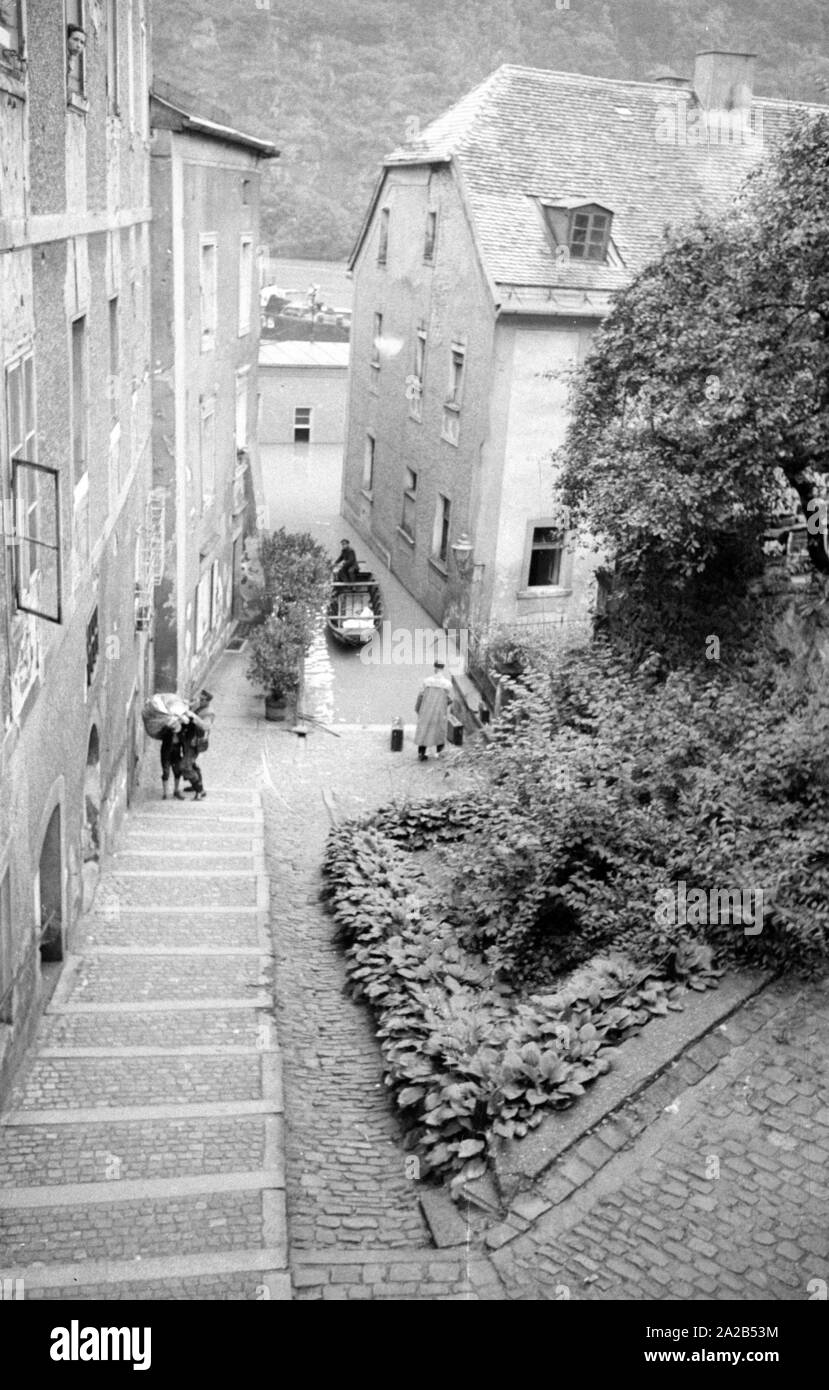 Die Flut in Passau und andere Teile von Niederbayern (Juli, 1954) wurden auch die Flut des Jahrhunderts bezeichnet. Die Donau, der Inn und die Ilz ueber die Ufer übergelaufen, und überflutete Städte und Dörfer. Foto von einem überfluteten Gasse und ein Anwohner auf dem Wasser mit einem Boot. Stockfoto