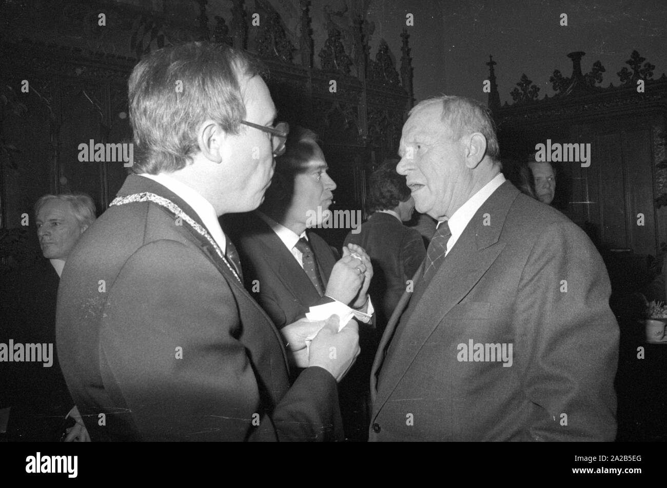 Das Bild zeigt die Schauspieler Gert Froebe (rechts) im Gespräch mit anderen Gästen der Feier der Gründung der Münchner Filmwoche. Stockfoto