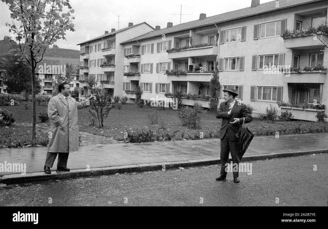 Zwei Männer haben ein Gespräch auf der Straße in Tuttlingen. Im Hintergrund ist ein Mehrfamilienhaus mit Mietwohnungen. Stockfoto