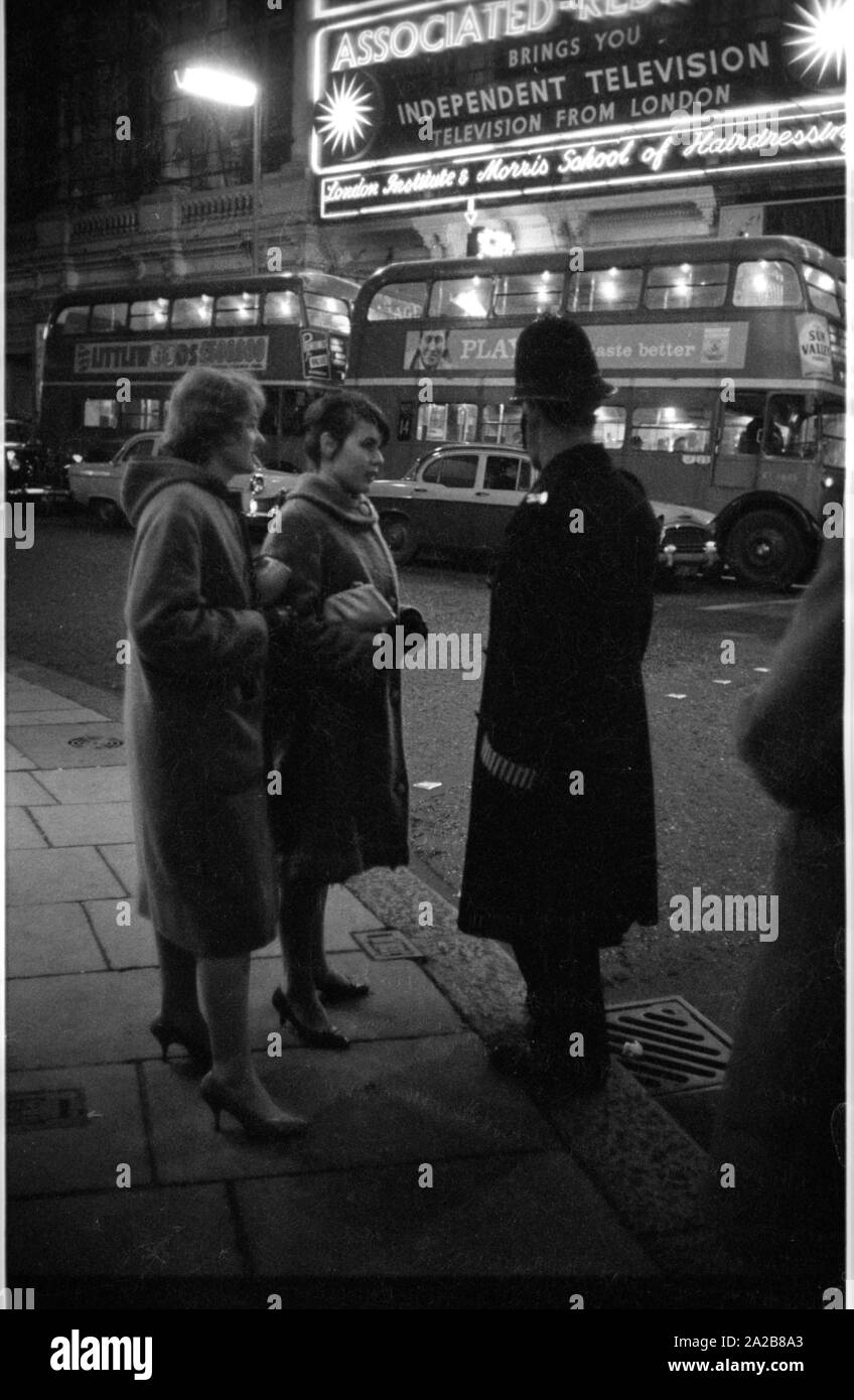 Frauen fragen, ein Polizist für Richtungen am Piccadilly Circus. Stockfoto