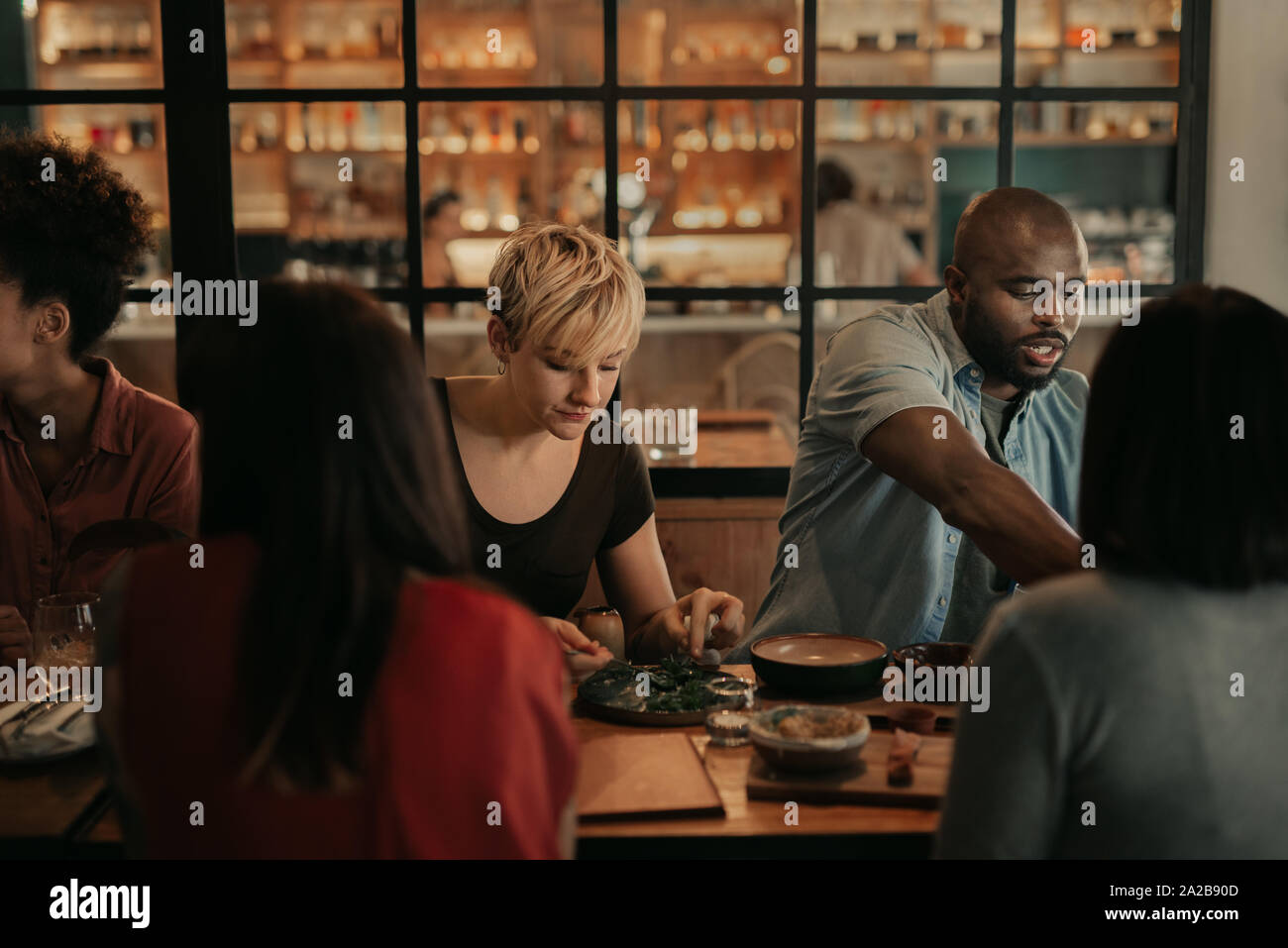 Vielfältige Gruppe von Freunden in einem Bistro Essen bei Nacht Stockfoto